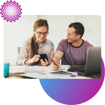 Two people reviewing their finances at a desk using their phone and laptop