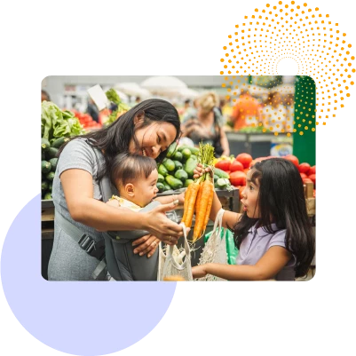 A mother and her children shopping and buying carrots at a grocery store